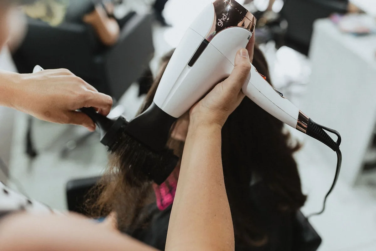 A stylist using a hairdryer and brush in the salon