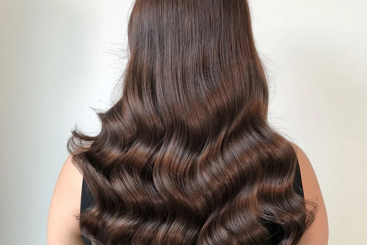 Long glossy brunette hair styled in sculpted waves