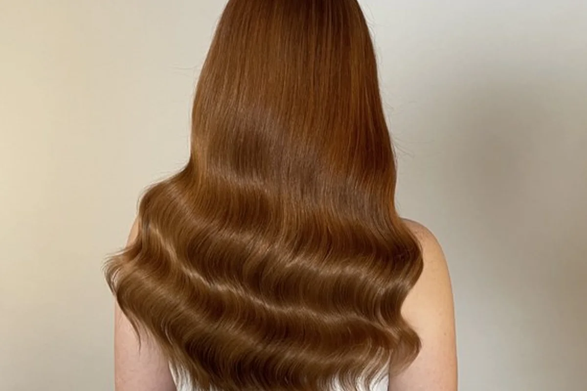 Long warm-toned hair with a polished wave