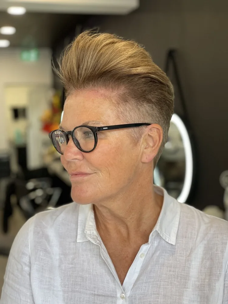 Short swept-up quiff with closely cropped sides, worn with glasses